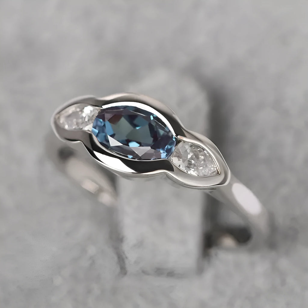 Geometric ellipse copper ring with inlaid zircon stones in white gold finish on a grey background