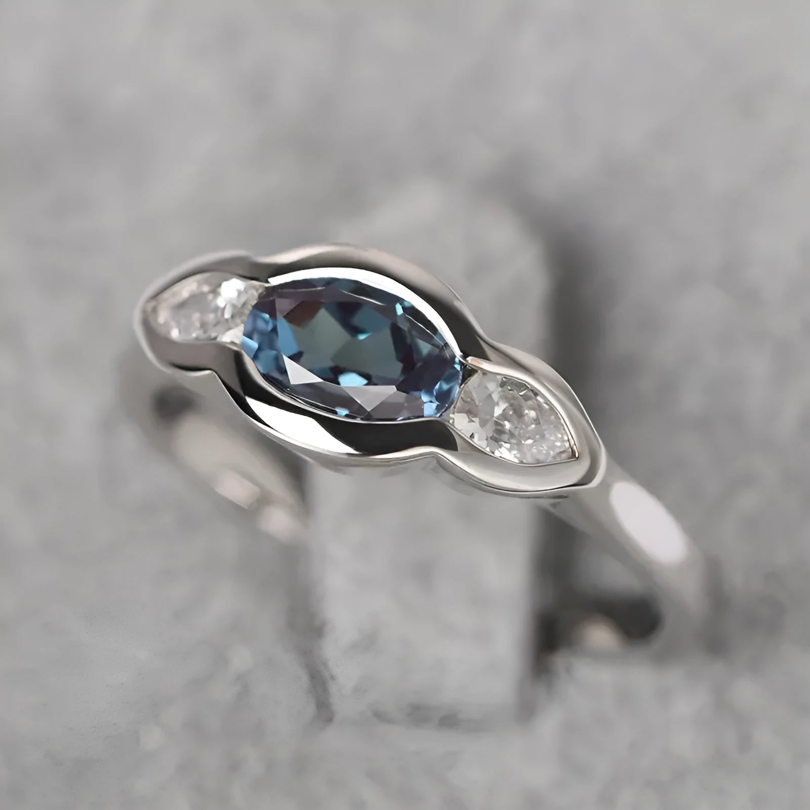 Geometric ellipse copper ring with inlaid zircon stones in white gold finish on a grey background