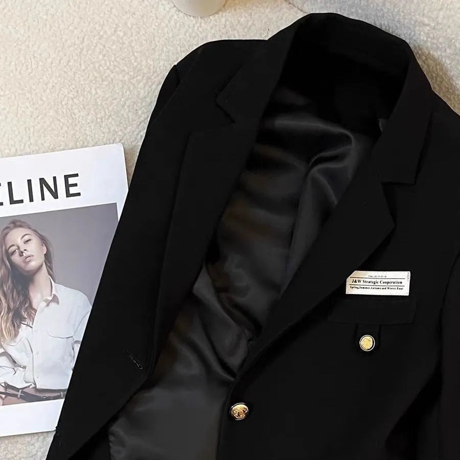 Black loose-fit women's short suit coat with long sleeves and pocket details.