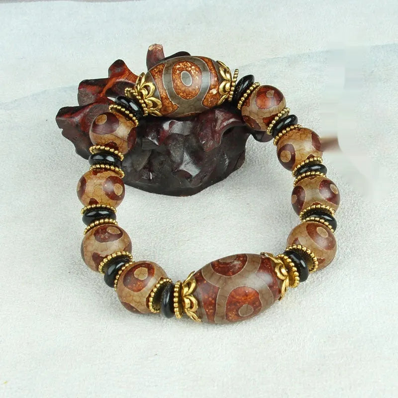 Distressed agate Tibetan bead bracelet with three-eye motifs and polished finish.