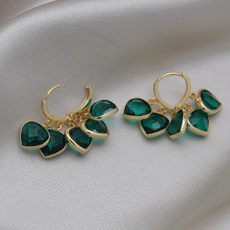 Pair of green heart-shaped glass pendant ear clip earrings with alloy inlay detail.