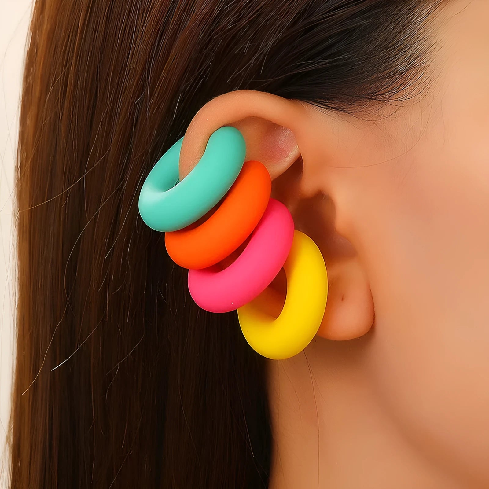 Geometric round C-shaped clip-on earrings in a matte coarse candy colour on a white background.
