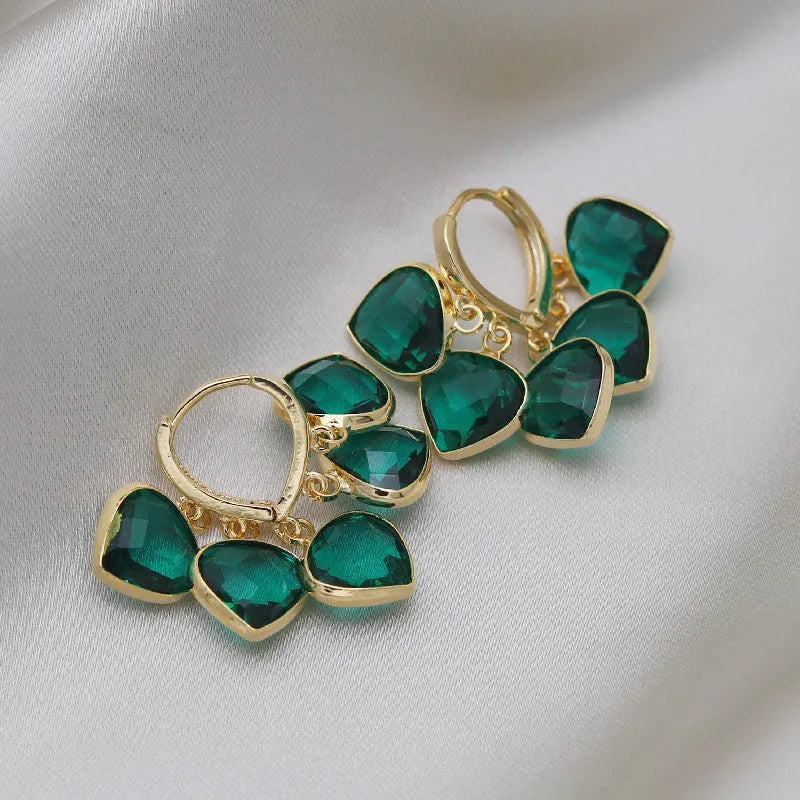 Pair of green heart-shaped glass pendant ear clip earrings with alloy inlay detail.