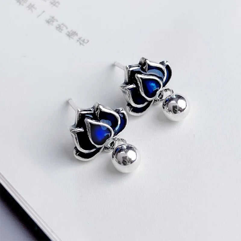 Blue alloy lotus flower stud earrings with a dangling seedpod tassel on silver posts.