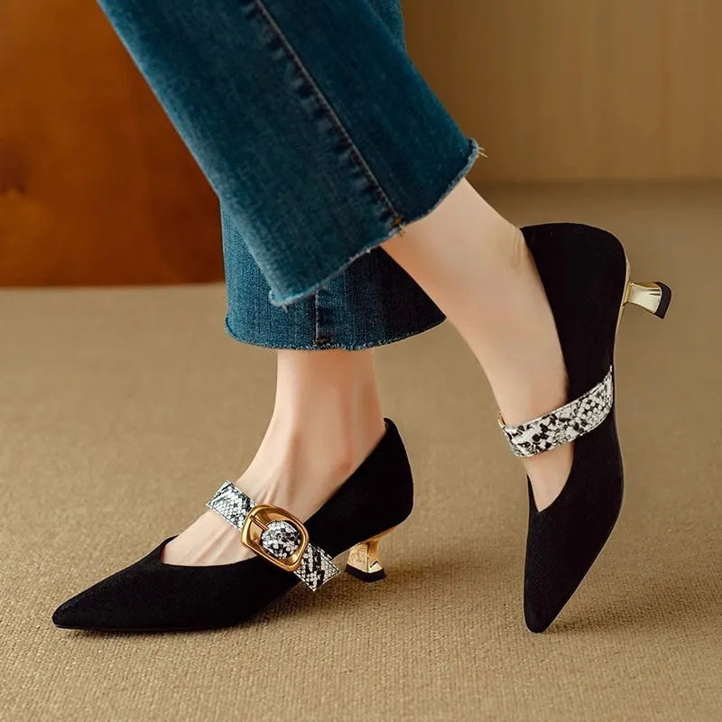Black women's pointed toe stiletto heels with an ankle buckle fastening on a white background.