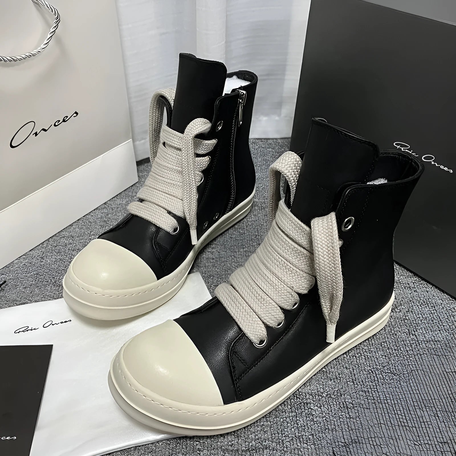 Men's and women's black high-top leather sneakers with a side zipper and round toe on a rubber sole.