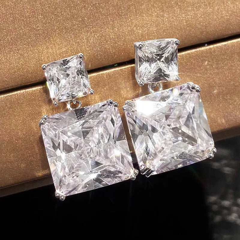 A pair of geometric square-shaped copper earrings in a white gold or golden colour finish.