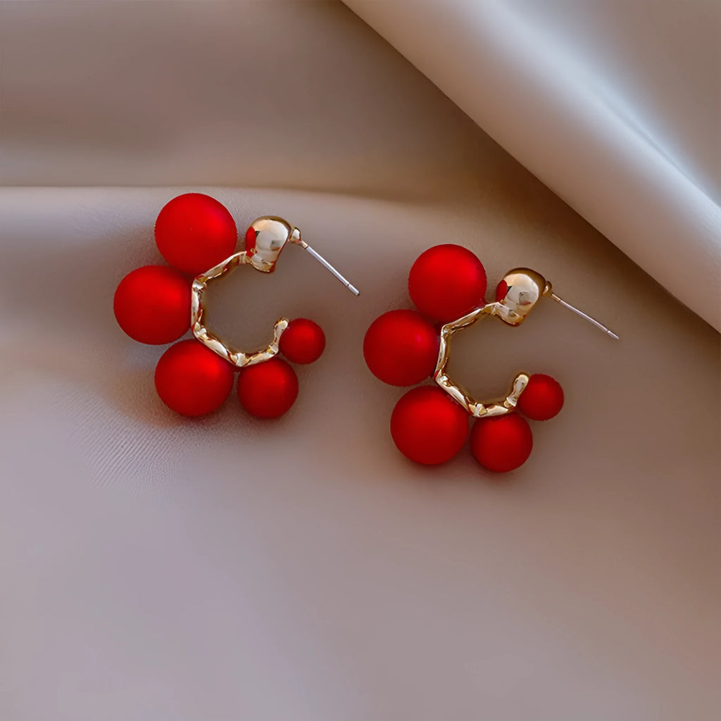 A pair of red bell-shaped alloy earrings for women on a white background.