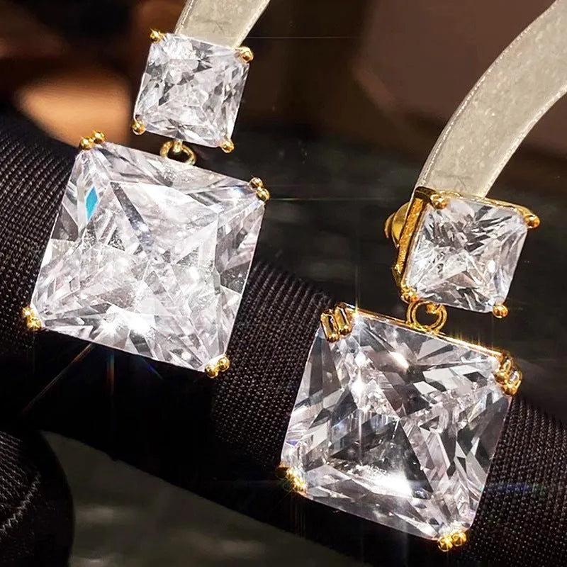 A pair of geometric square-shaped copper earrings in a white gold or golden colour finish.