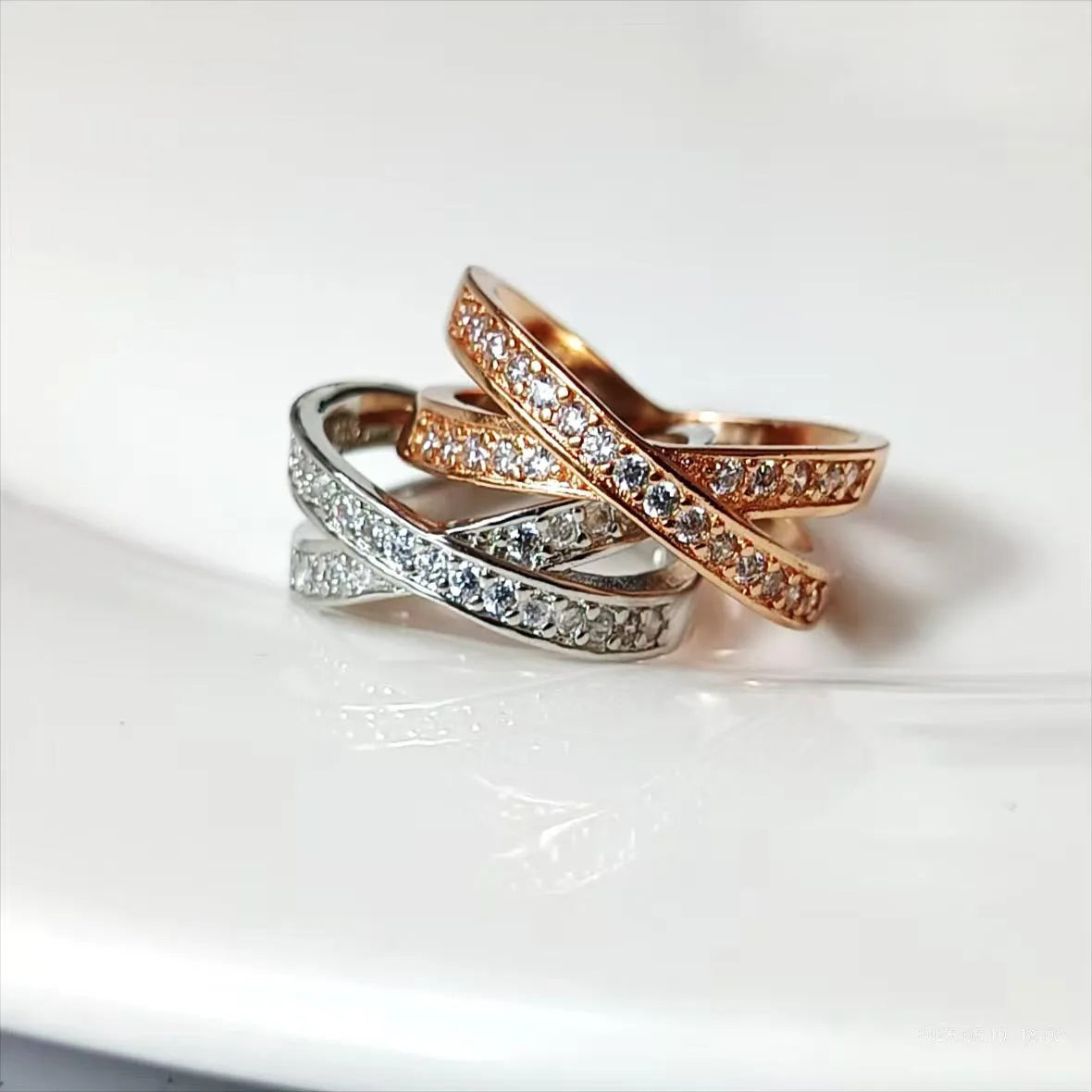 Silver and rose gold cross ring with micro-inlaid zircon stones on a simple geometric band.