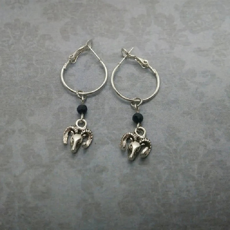 A pair of silver-coloured round hoop earrings with a detailed Tibetan antelope design.