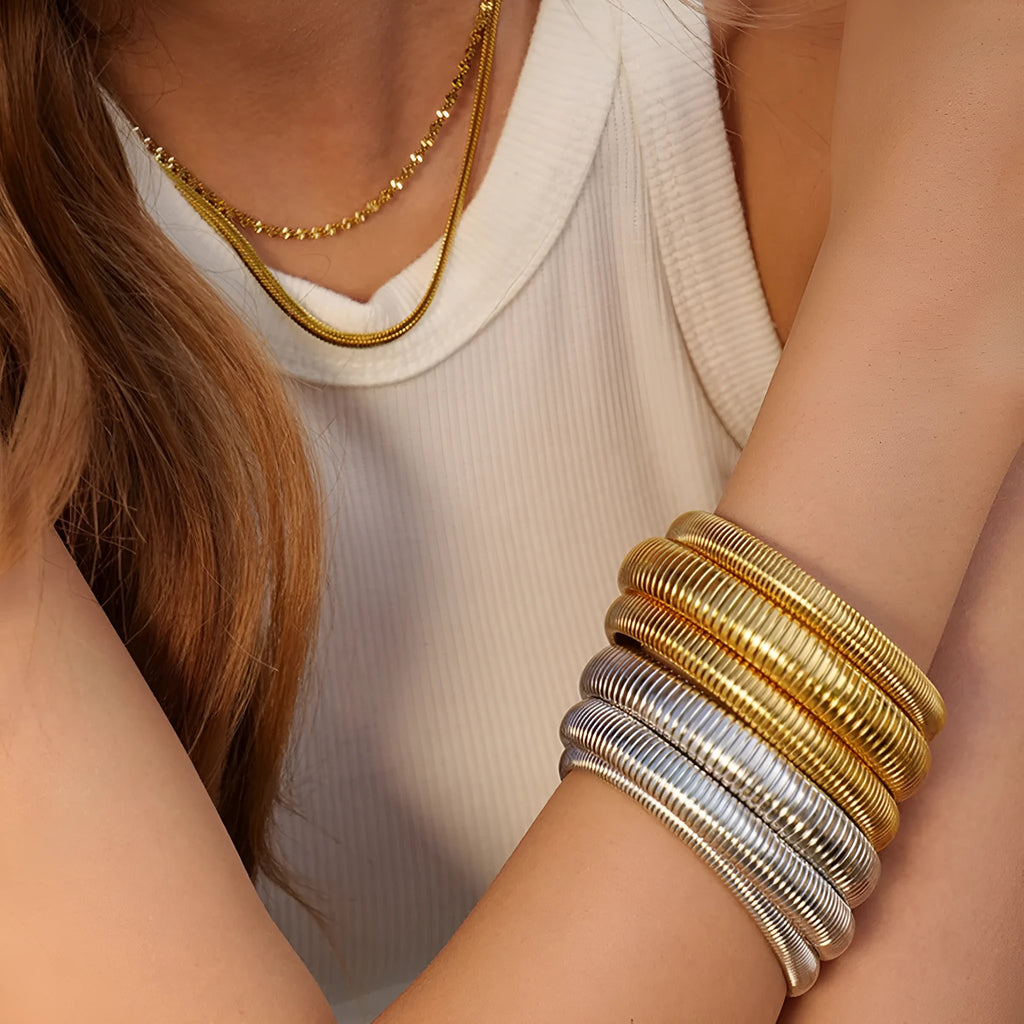 Women's vertical stripe ring titanium steel bracelet in gold and silver colours showing elastic construction.