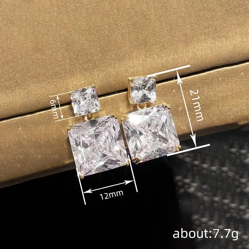 A pair of geometric square-shaped copper earrings in a white gold or golden colour finish.