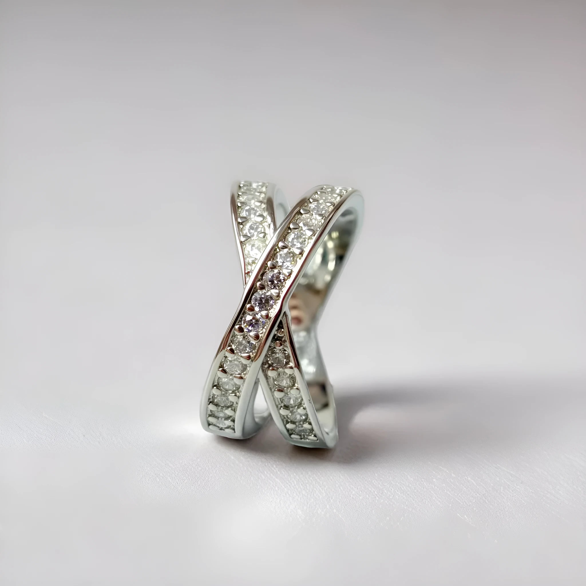 Silver and rose gold cross ring with micro-inlaid zircon stones on a simple geometric band.