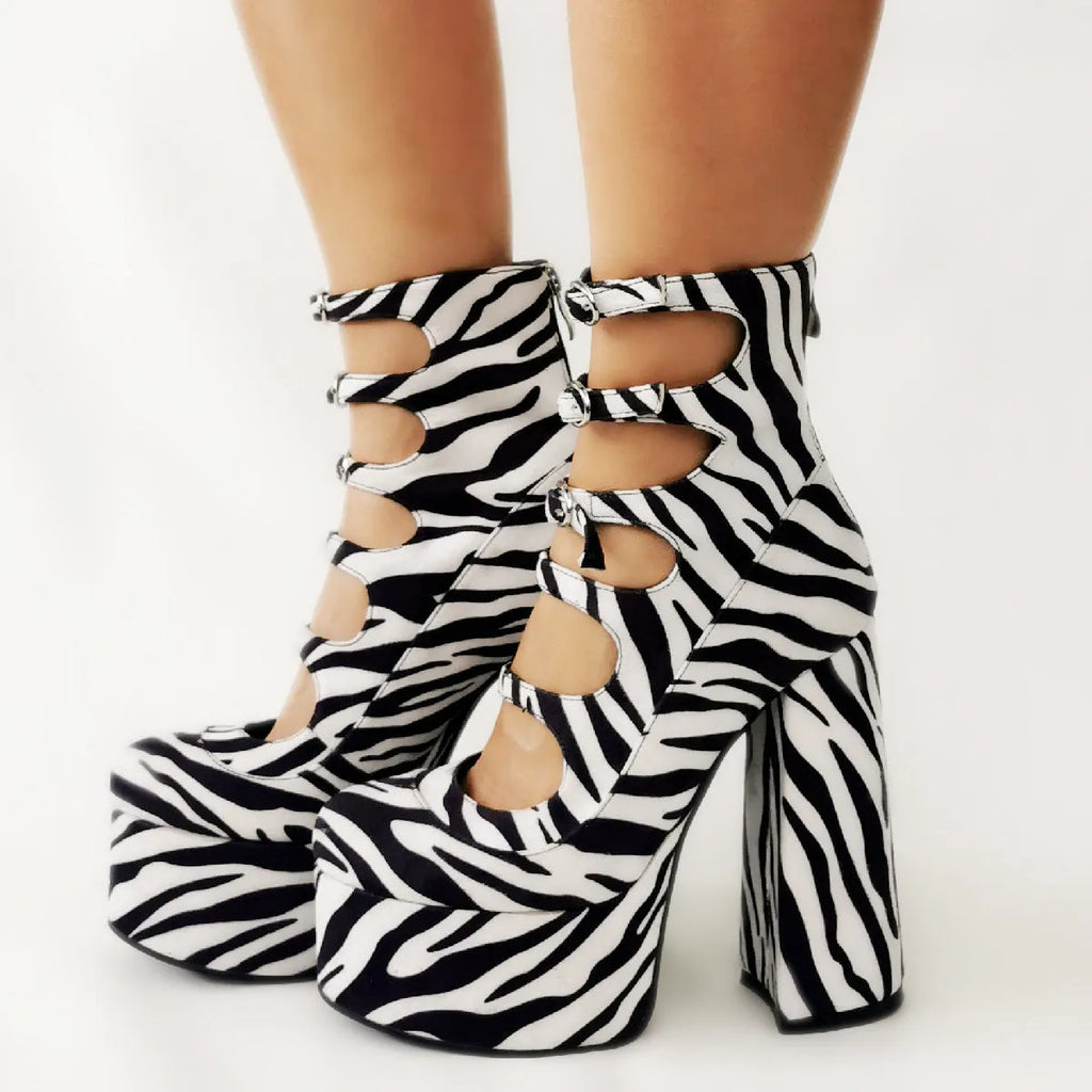 Women's black patent leather platform high heel boots with a serpentine belt and buckle closure.