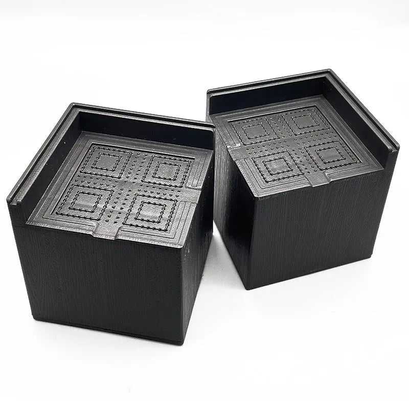 Four black plastic furniture foot mats for bed or sofa height adjustment.