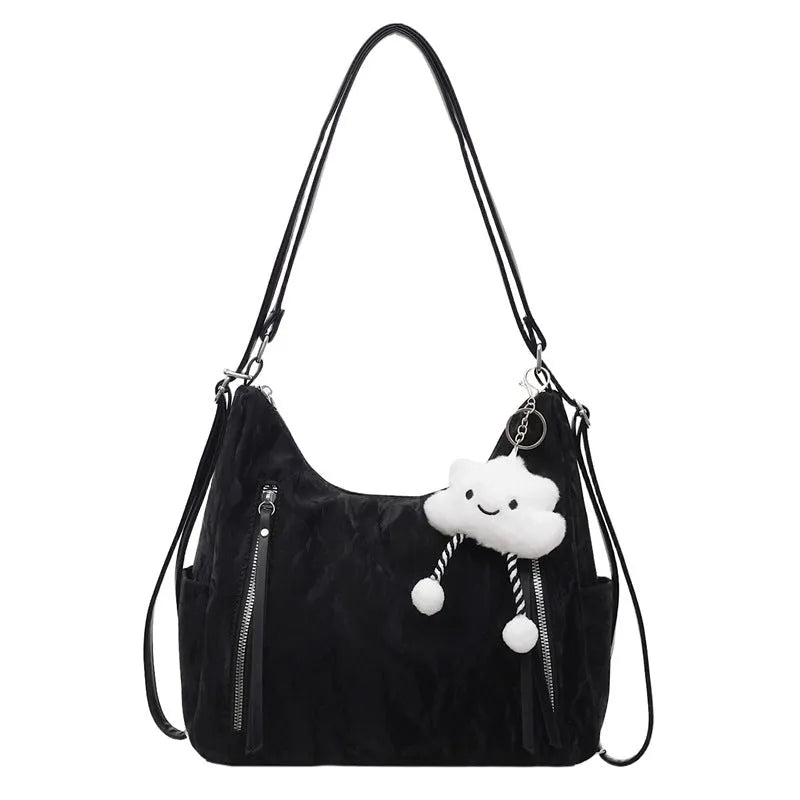 Women's soft black PU fashion backpack with a pendant accessory on a table.