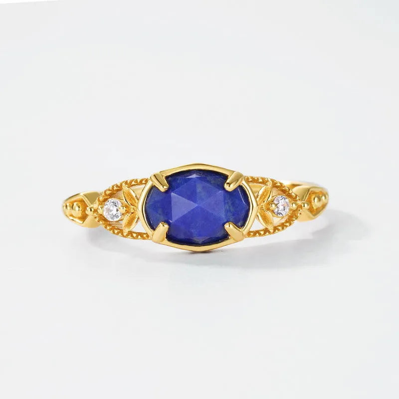 Close-up of a silver elliptical ring with a deep blue lapis lazuli stone set in a geometric band.