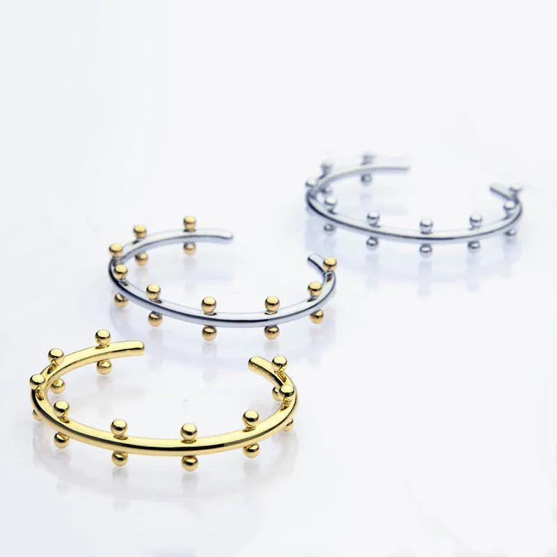 Stainless steel bracelet with textured C-shaped bead links and raised rivet details.