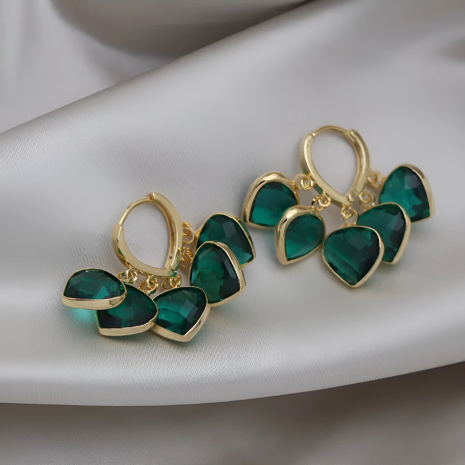 Pair of green heart-shaped glass pendant ear clip earrings with alloy inlay detail.