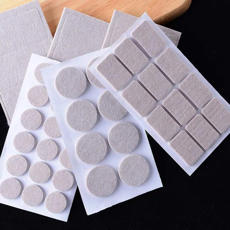 Assortment of beige plastic furniture leg protection pads in round and square sizes on wooden floor