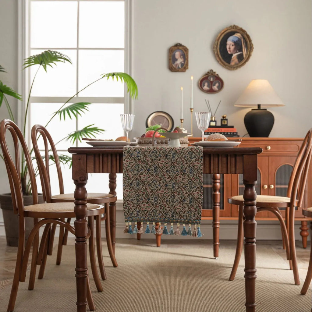Dark blue striped table runner with jacquard bouquet pattern and tassel ends on a wooden table.