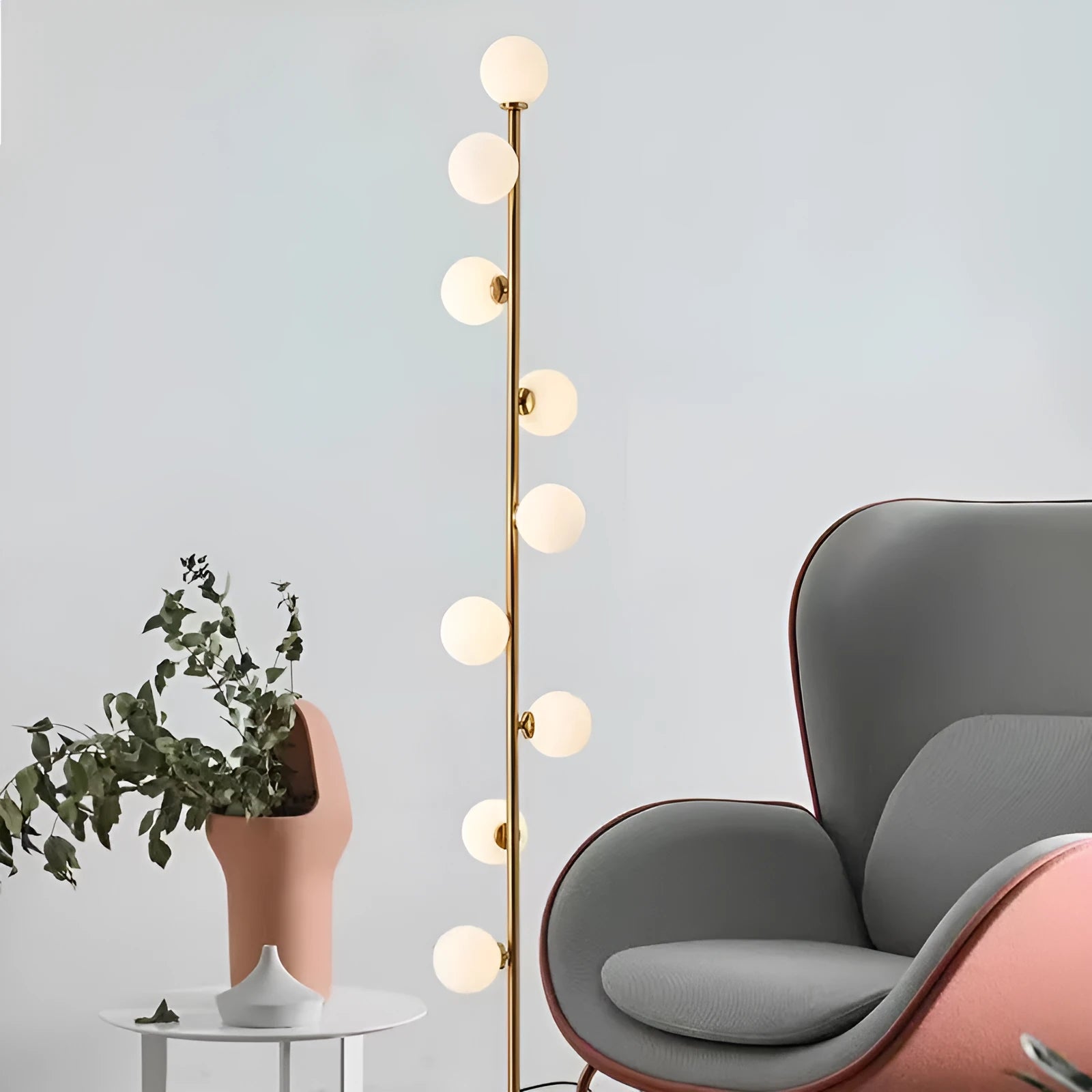 A tall, modern minimalist floor lamp with a wrought iron and glass body standing on a circular marble base.