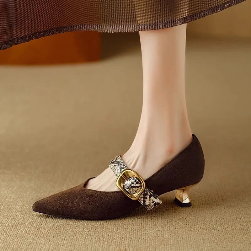 Black women's pointed toe stiletto heels with an ankle buckle fastening on a white background.