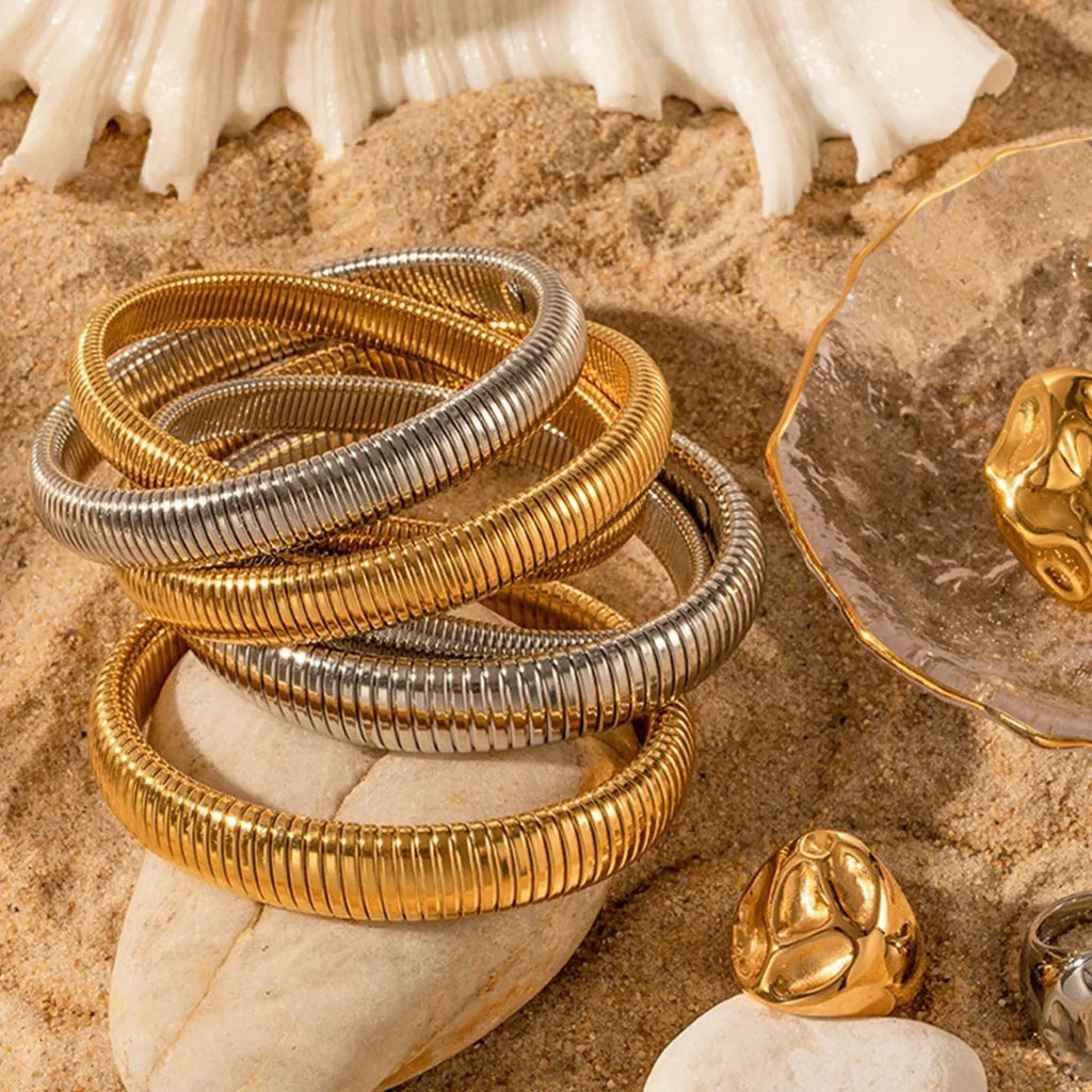 Women's vertical stripe ring titanium steel bracelet in gold and silver colours showing elastic construction.