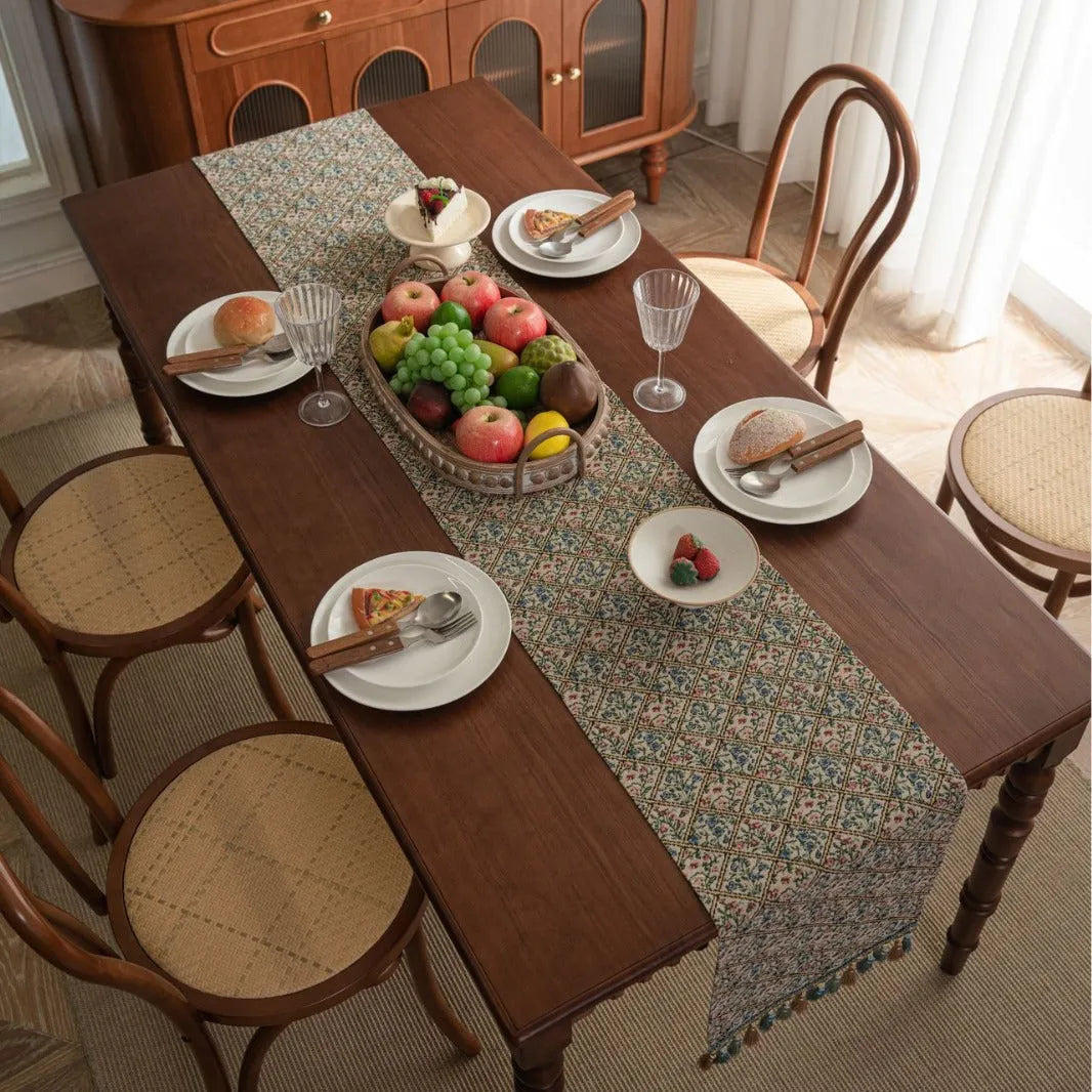 Dark blue striped table runner with jacquard bouquet pattern and tassel ends on a wooden table.