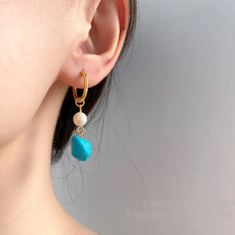 A pair of geometric copper earrings with irregular turquoise stones and cultured pearls