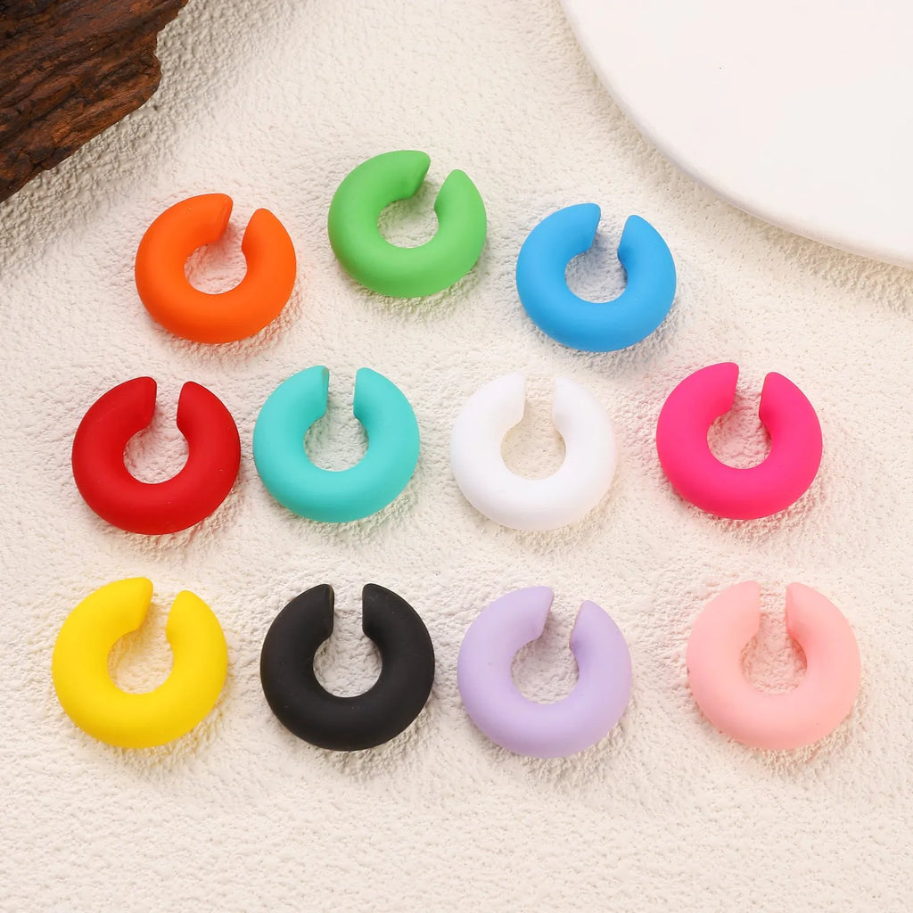 Geometric round C-shaped clip-on earrings in a matte coarse candy colour on a white background.