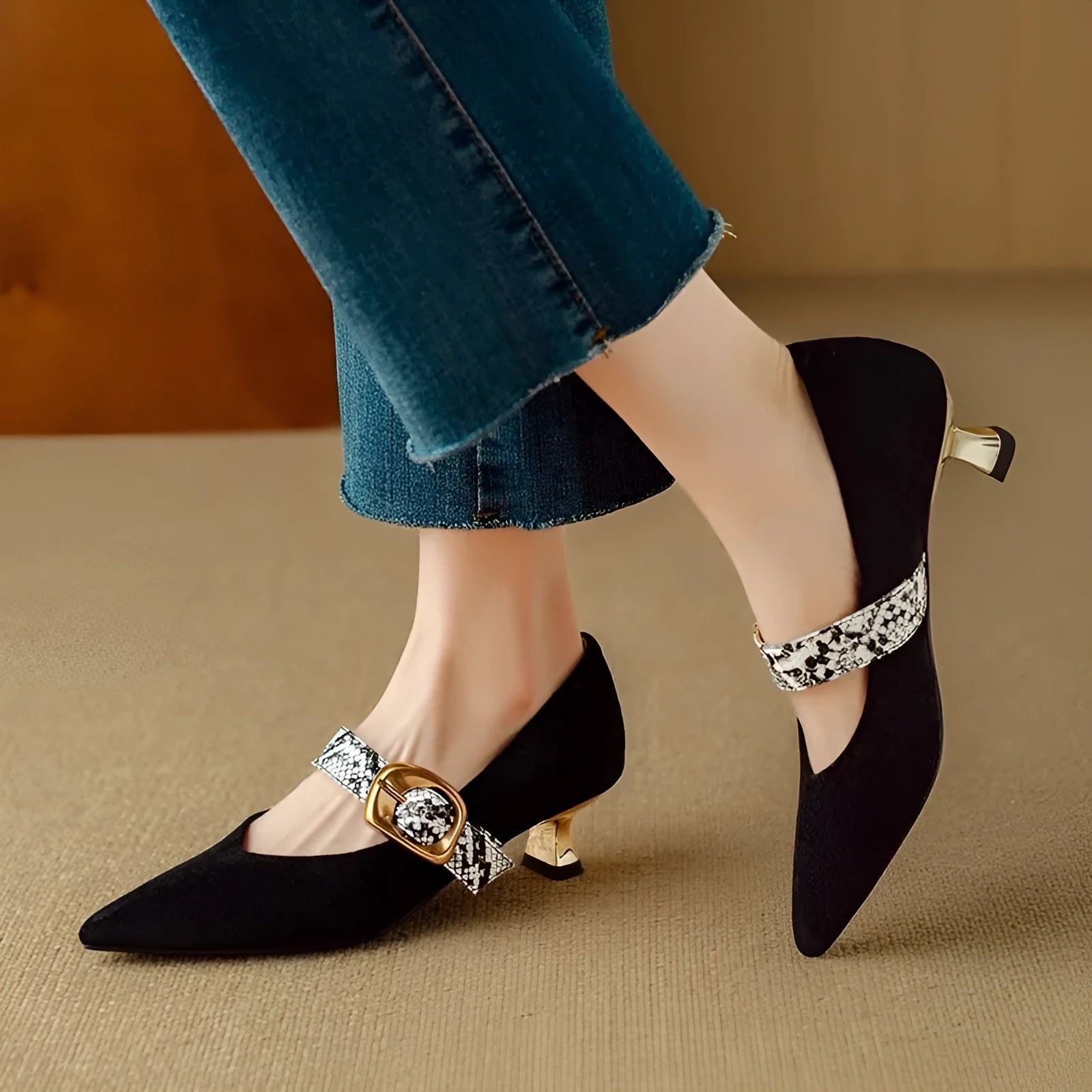 Black women's pointed toe stiletto heels with an ankle buckle fastening on a white background.