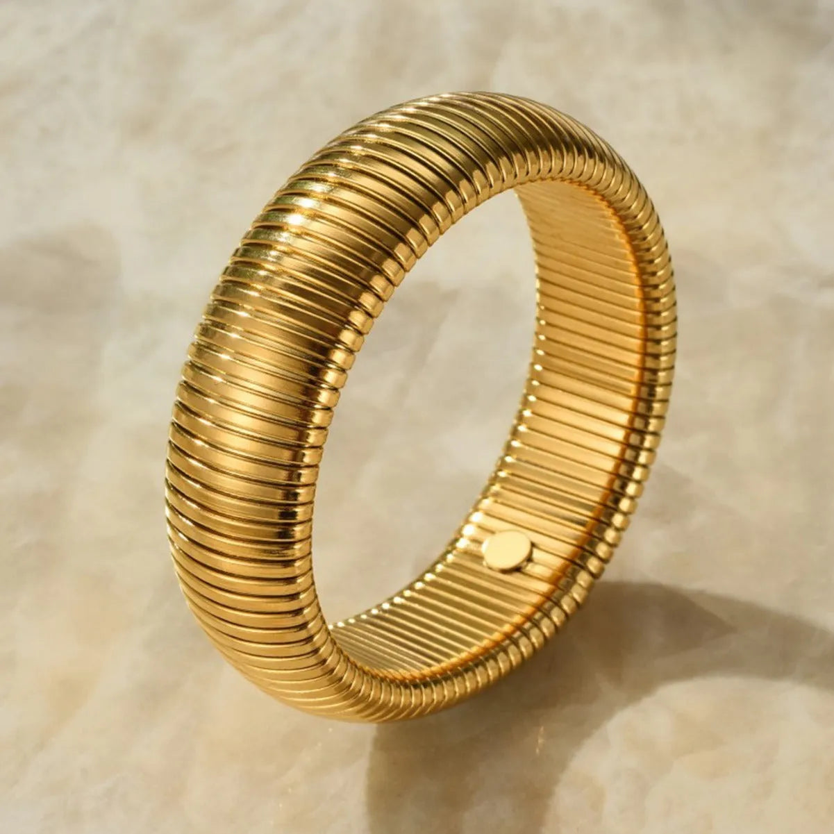 Women's vertical stripe ring titanium steel bracelet in gold and silver colours showing elastic construction.