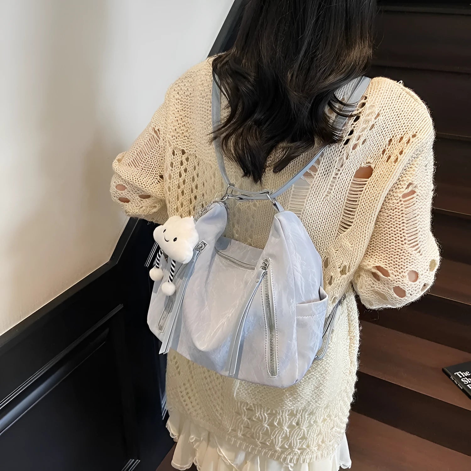 Women's soft black PU fashion backpack with a pendant accessory on a table.
