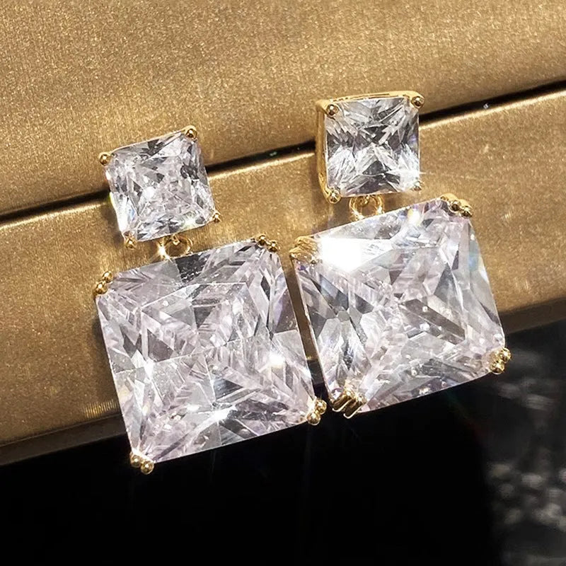 A pair of geometric square-shaped copper earrings in a white gold or golden colour finish.
