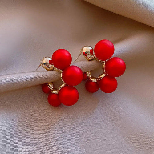 A pair of red bell-shaped alloy earrings for women on a white background.