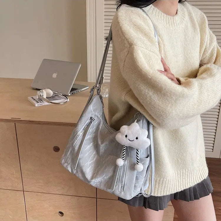 Women's soft black PU fashion backpack with a pendant accessory on a table.