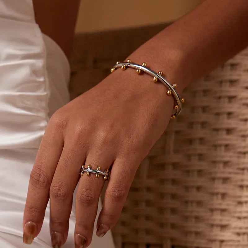 Stainless steel bracelet with textured C-shaped bead links and raised rivet details.