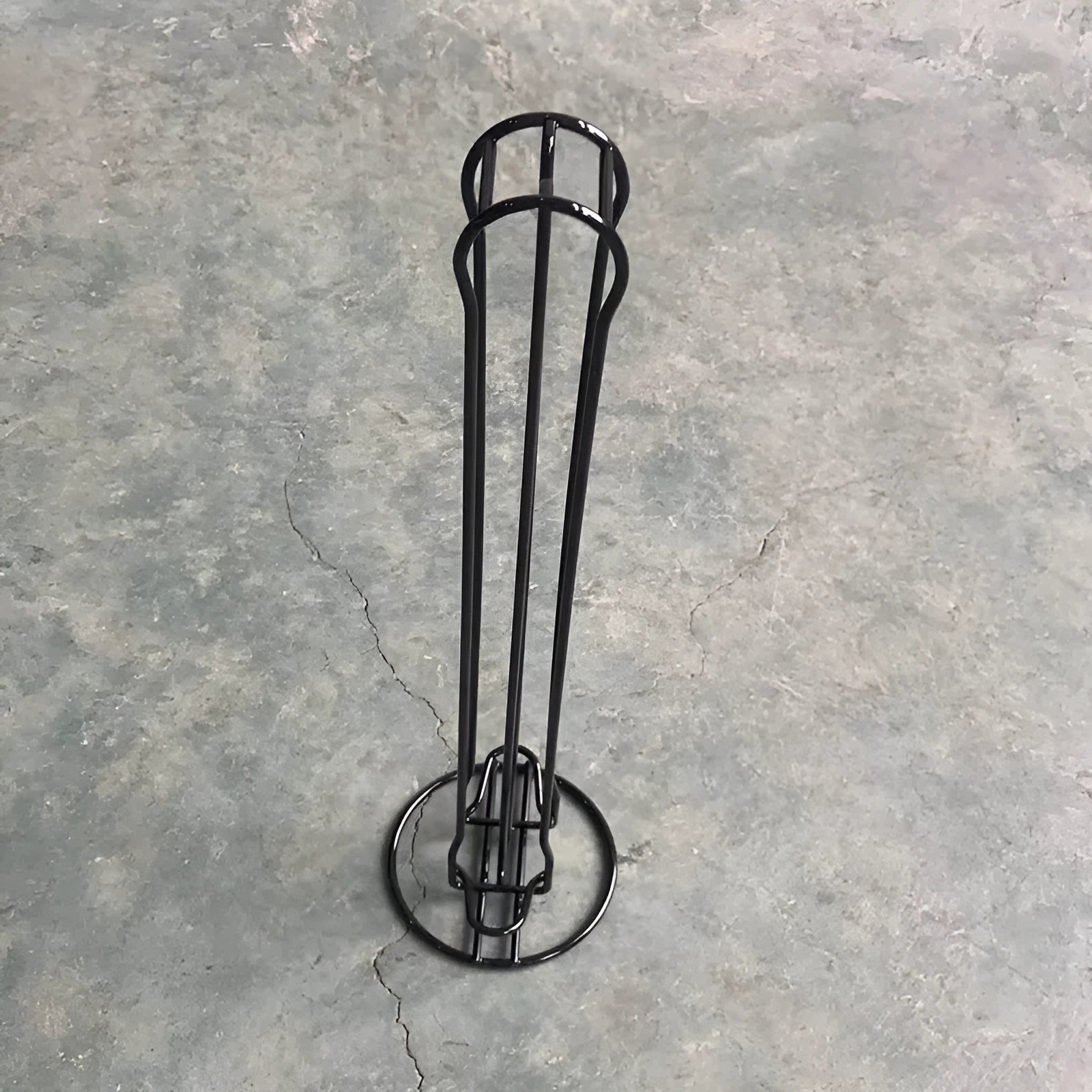Black wrought iron coffee capsule storage rack holding pods on shelves