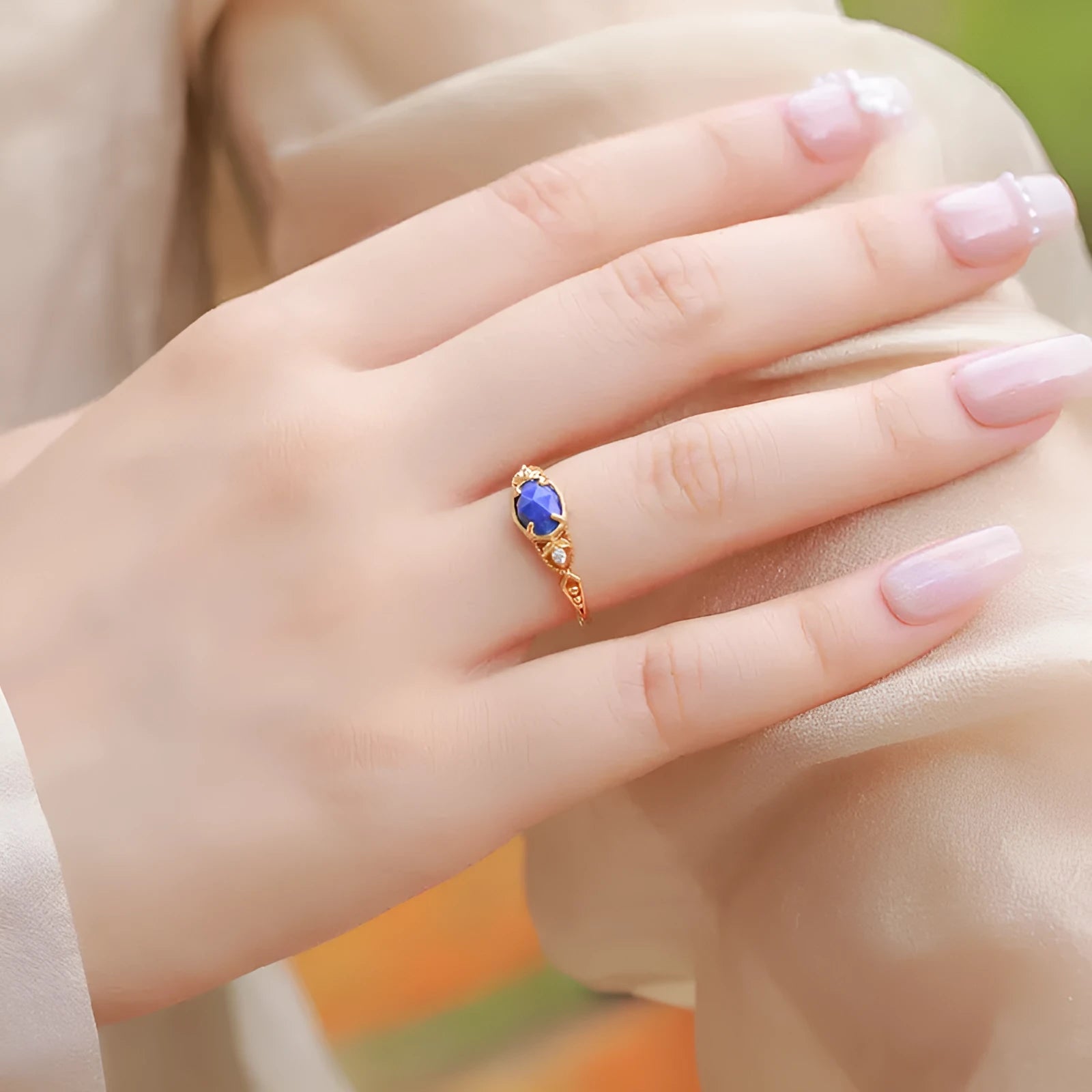 Close-up of a silver elliptical ring with a deep blue lapis lazuli stone set in a geometric band.
