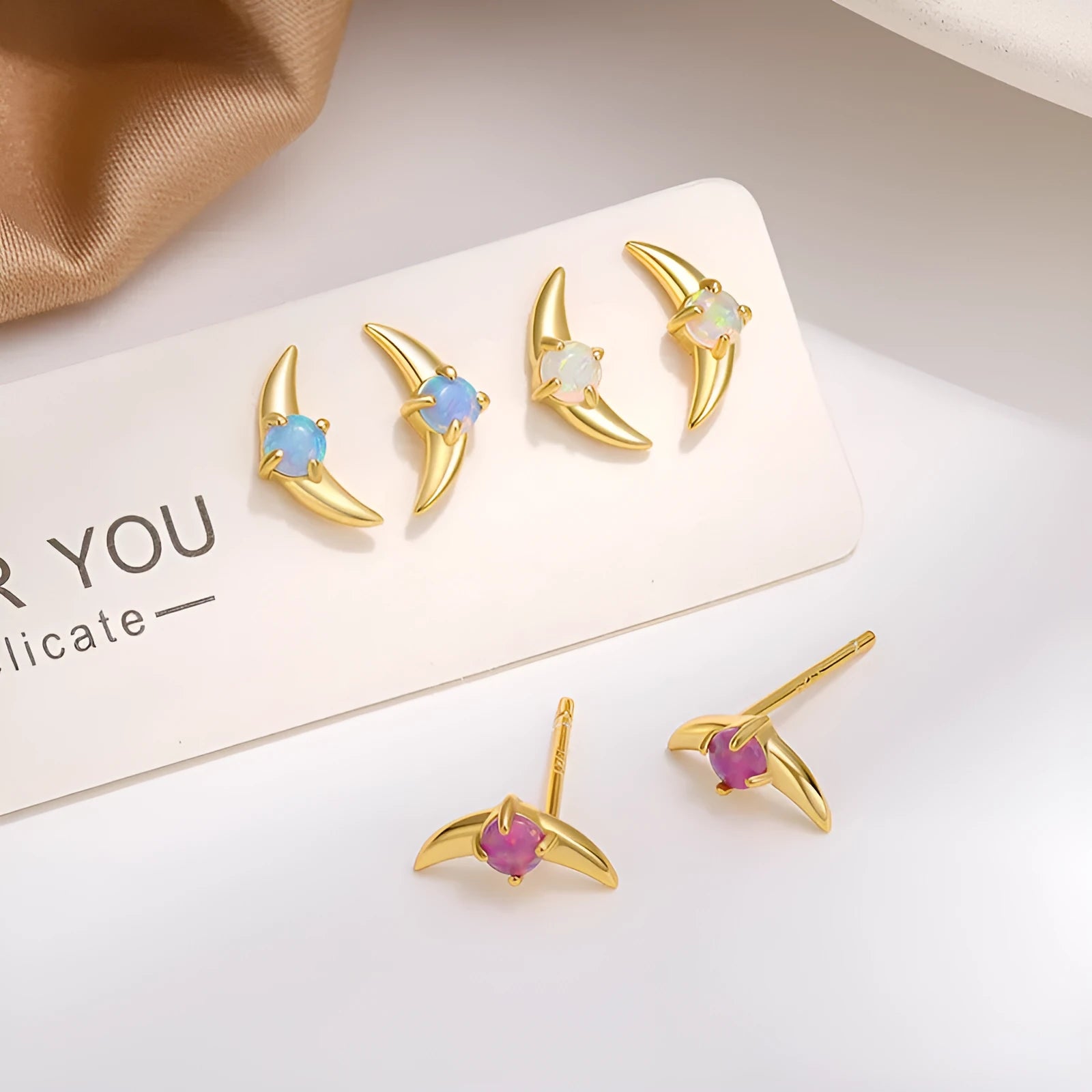 A pair of geometric-shaped sterling silver earrings with a gold-plated finish and a central blue zirconia stone.