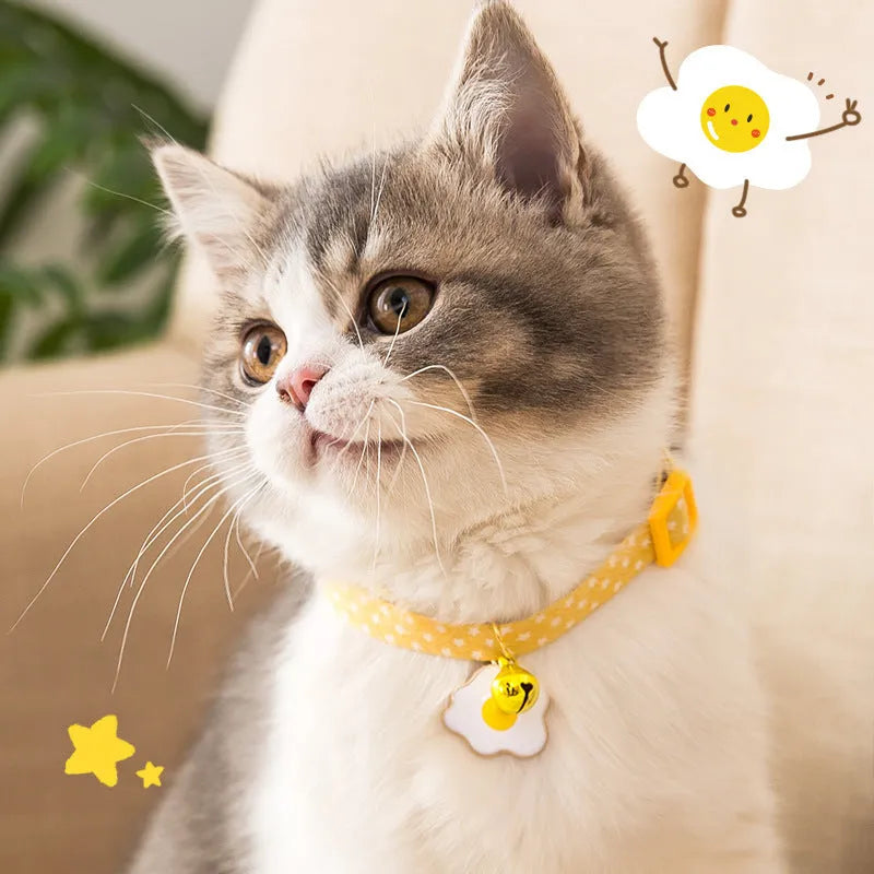 Green adjustable cat collar with a small bell and bow tie pendant on a white background.