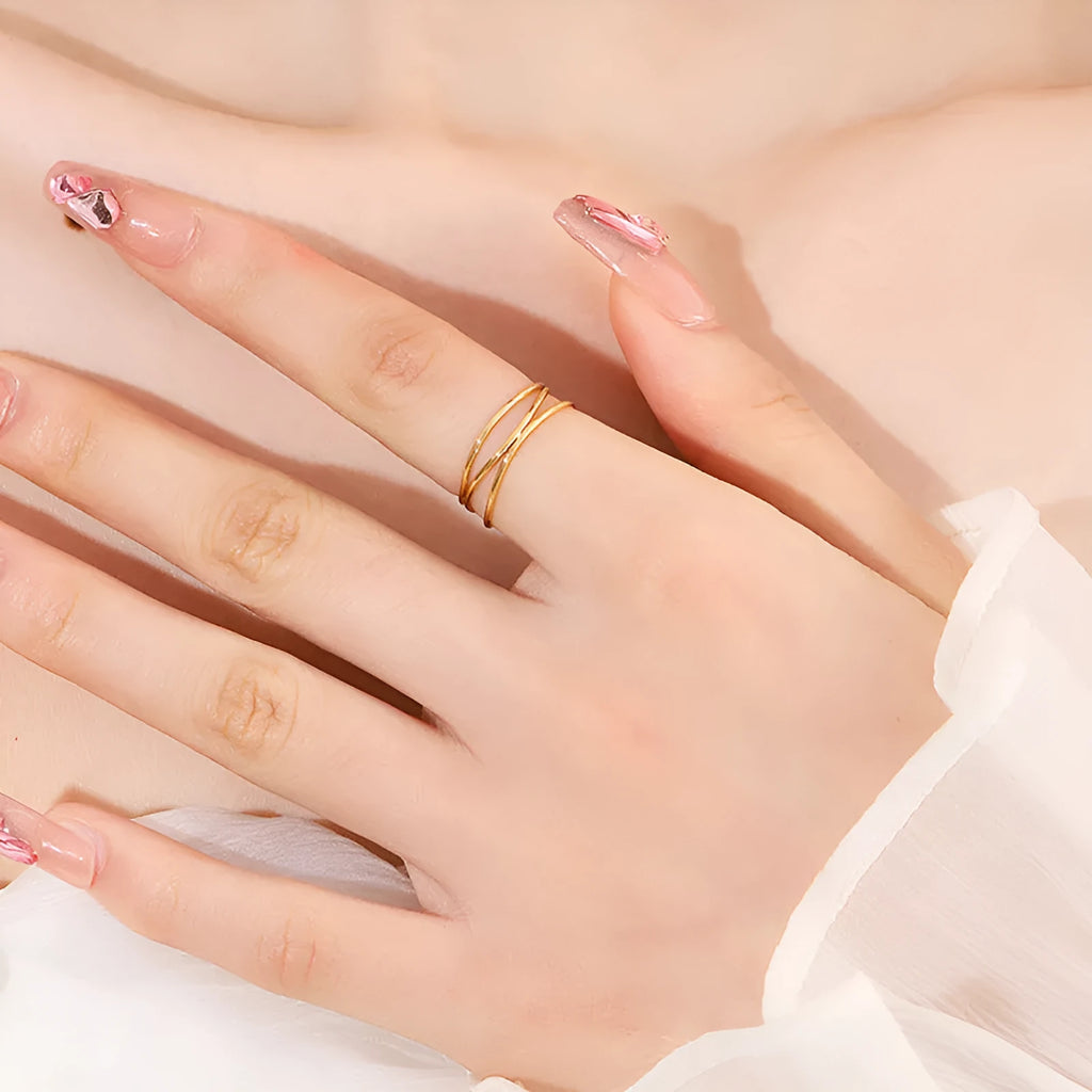 Gold-coloured titanium steel geometric ring with a three-layer coil design on a plain background.