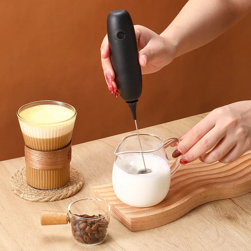 Hand-held electric milk frother blender in black or white colour for coffee preparation