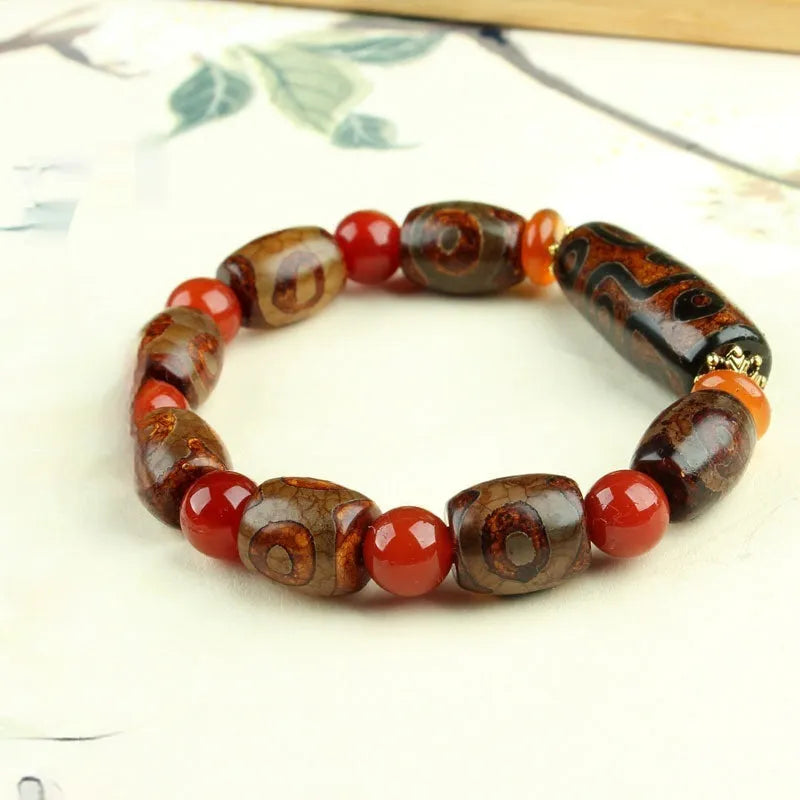 Distressed agate Tibetan bead bracelet with three-eye motifs and polished finish.