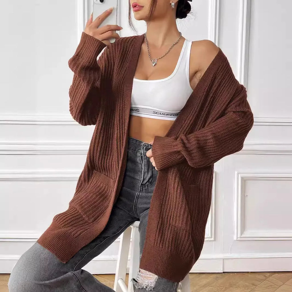 A women's loose dark green cardigan sweater with two pockets and long sleeves.