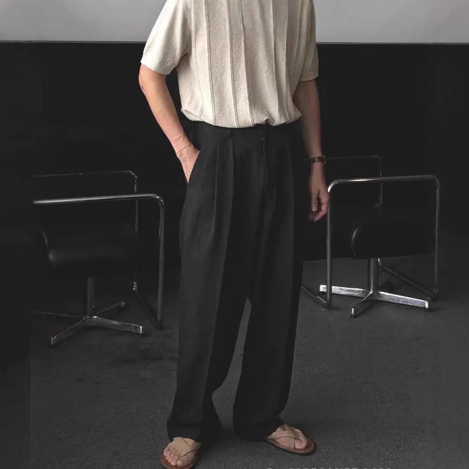 Man wearing loose fit apricot wide-leg cotton linen trousers with a zip fly and straight leg opening.