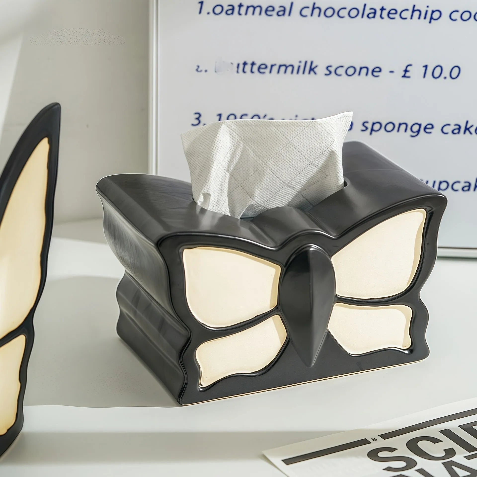 Ceramic butterfly vase and matching tissue box set on a living room table.