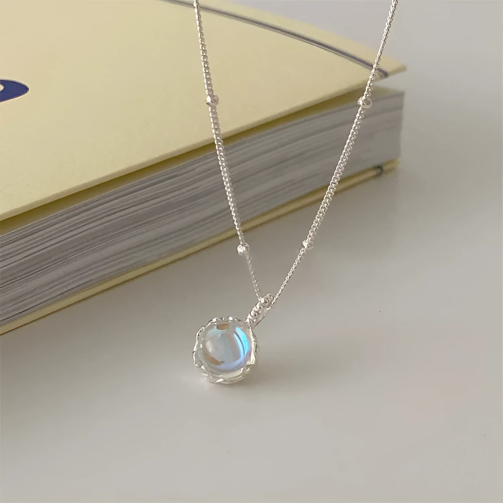 Women's sterling silver curb chain necklace with a geometric ornamental stone pendant on a grey background.